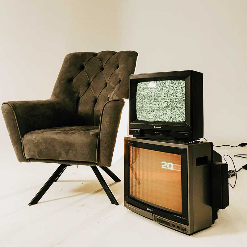 Un fauteuil, à côté deux postes de télévision représentant la publicité.