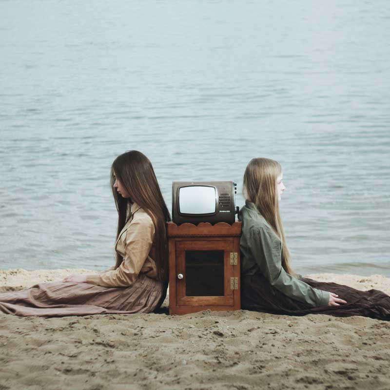 Une télévsion entre deux jeunes femmes assises sur la plage